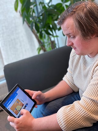 Mann som ser på et nettbrett som viser en matematikkoppgave med tittelen "Hvor mange er det?"